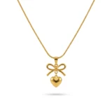 Gold bow necklace with a dangling heart pendant on a thin snake chain.
