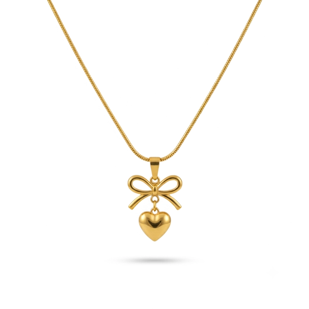 Gold bow necklace with a dangling heart pendant on a thin snake chain.
