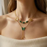Gold layered necklace with green stones and butterfly pendant