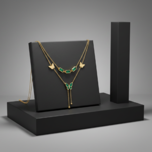 A gold double-layered necklace featuring green baguette-cut stones and butterfly charms on a black display stand.