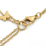Gold layered necklace with green stones and butterfly pendant.