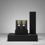 Pair of gold-plated square LV monogram earrings with white pearl drops on a black leather jewelry stand.