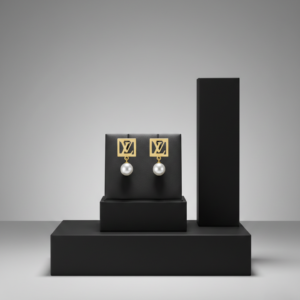 Pair of gold-plated square LV monogram earrings with white pearl drops on a black leather jewelry stand.