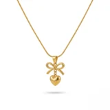 Gold bow necklace with a dangling heart pendant on a thin snake chain.