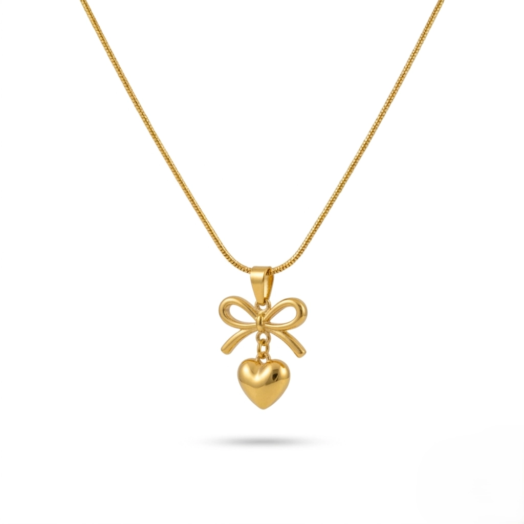 Gold bow necklace with a dangling heart pendant on a thin snake chain.