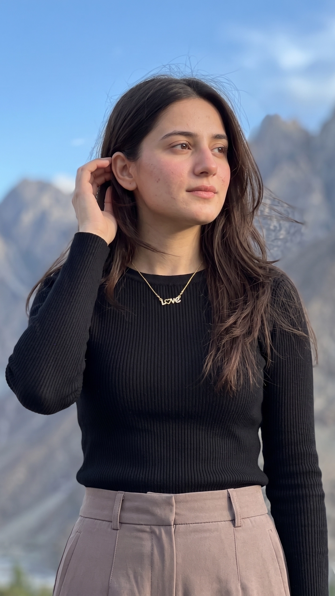 Gold script necklace spelling "Love" with a paved crystal heart as the letter O.