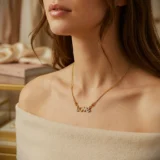 Gold script necklace spelling "Love" with a paved crystal heart as the letter O.