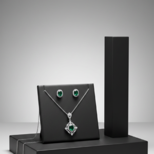 Elegant emerald green gemstone pendant and matching stud earrings on a black jewelry display stand.