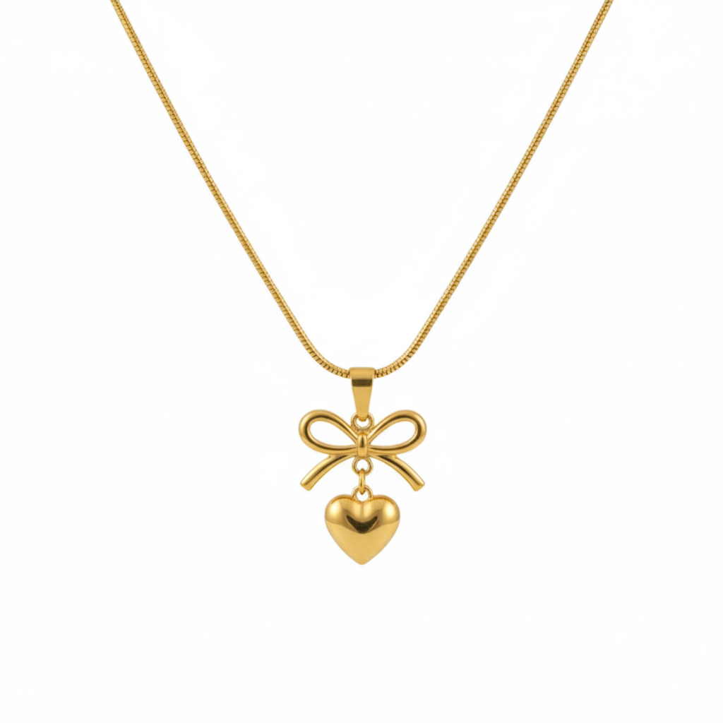 Gold bow and heart pendant necklace on a gold snake chain, isolated on a white background.