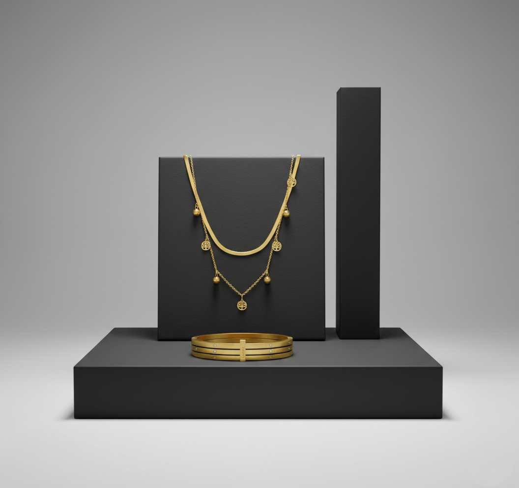 Gold Layered Tree of Life Necklace and Bangle Set on Minimalist Black Pedestal A gold layered necklace with tree of life charms and a matching gold bangle displayed on matte black geometric stands.