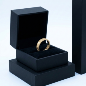 A premium gold ribbed stainless steel ring displayed in an open black jewelry box.