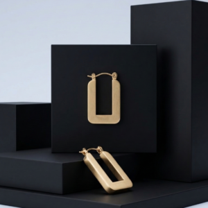 Pair of modern matte gold rectangular stainless steel hoop earrings on a black aesthetic background.