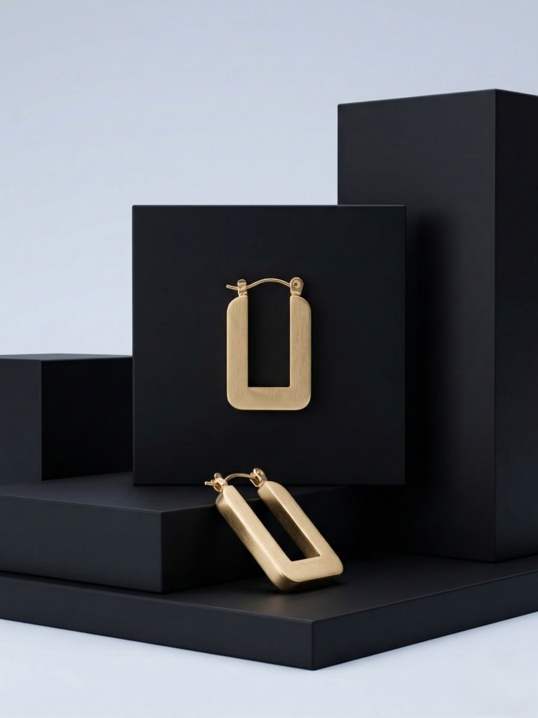 matte-gold-stainless-steel-rectangular-earrings.jpg Pair of modern matte gold rectangular stainless steel hoop earrings on a black aesthetic background.