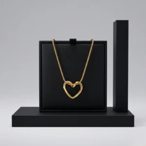 A gold-toned heart pendant necklace on a delicate snake chain against a clean, white background.