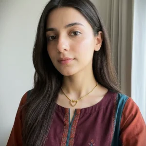 A gold-toned heart pendant necklace on a delicate snake chain against a clean, white background.